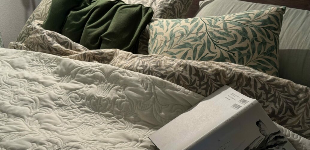 ウィリアム・モリスの寝具に囲まれたベッドで、眠る前に本を読む時間